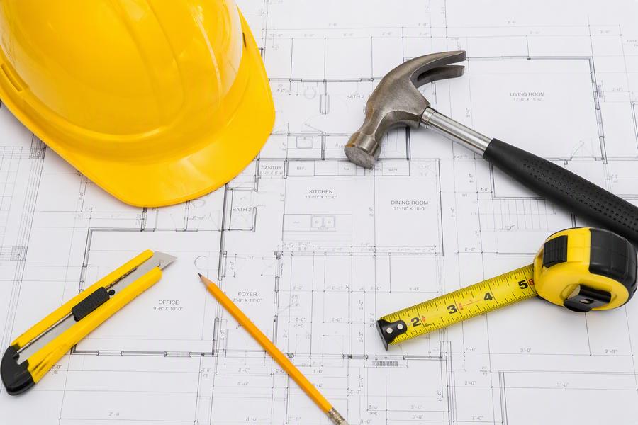 Construction tools and hard hat on blueprints