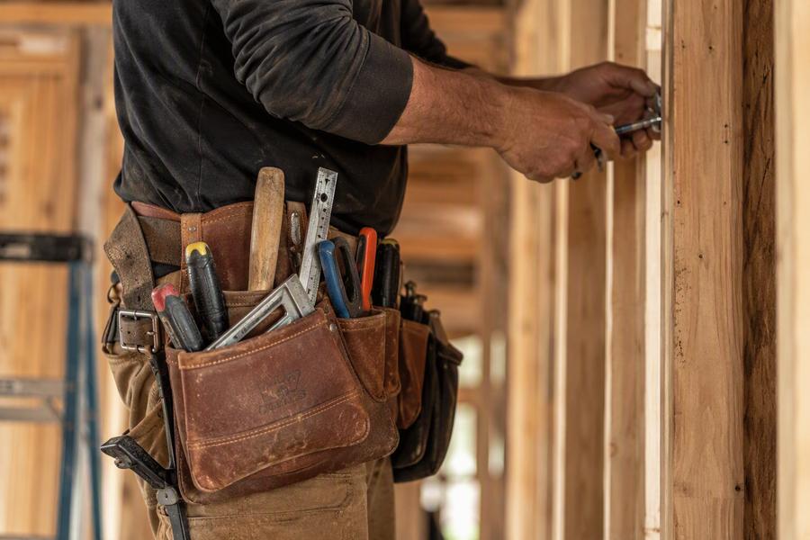Tradesman with tool belt working on wood framing
